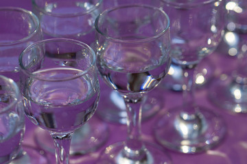 Elegant water glasses served on violet table, close up, top view