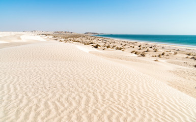 Landscape of Al Khaluf beach with dunes and white sands in the Arabian Sea of Oman.