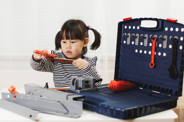 toddler girl pretend using DIY tool at home against white backgrround