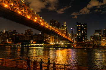 Naklejka na ściany i meble People standing in front of a bridge at night