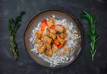 Tasty rice with chicken, rosemary and thyme on black background