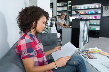 woman reads a magazine while waiting in a hairdressing salon