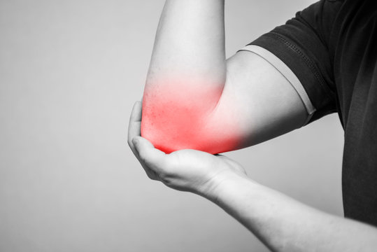 Man with pain in elbow. Ache in the human body on a gray background with red dot. Pain relief concept