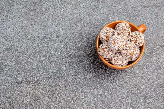 Energy balls made of dates, nuts, oats sprinkled with coconut powder close-up on a gray background