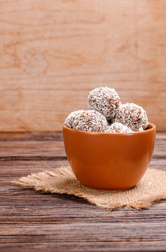 Balls of energy dates, nuts, oats, sprinkled with coconut powder close-up on a wooden background