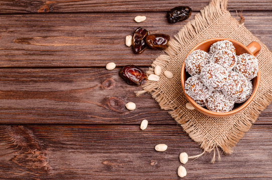 Balls of energy dates, nuts, oats, sprinkled with coconut powder close-up on a wooden background