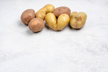 Despicable potatoes of different shapes on a gray background, copy space