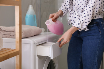Woman pouring detergent into washing machine drawer in bathroom, closeup. Laundry day