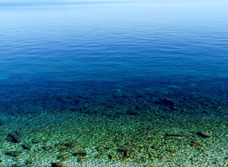 Fototapeta na wymiar Vivid blue and green colors of shallow water marine environment. Beautiful nature background with transparent sea surface and rocks below it