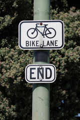 Close-up view of a traffic sign combination on a lamp pole saying BIKE LANE END
