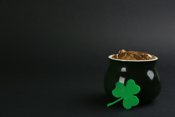 Pot of gold coins and clover on black background, space for text. St. Patrick's Day celebration
