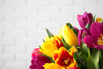 Beautiful spring tulips against white brick wall, closeup. Space for text