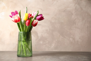 Beautiful spring tulips in vase on table against light background. Space for text