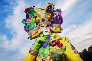 The anonimous person in the bright traditional fashionable Venice carnival costume with the mask