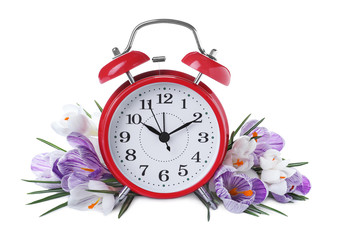 Red alarm clock and spring flowers on white background. Time change