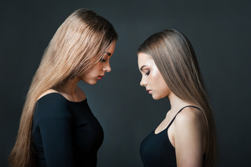 sisters - girlfriends, facing each other, silhouette on dark background