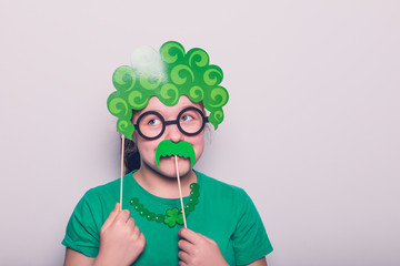 Young girl is preparing for the St Patricks Day party with photo booth props, Ireland traditional holiday, 17 March