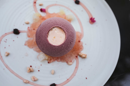 High angle close up of plate of dessert with with a cassis bombe and elderflower yoghurt, choya granita and yuzu pearls.,Singapore