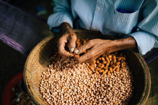 High angle close up of man shelling peanuts outside of his house.,Hoi An