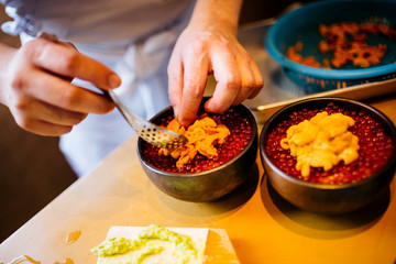 High angle close up of chef preparing uni, sea urchin, with salmon roe and rice.,Otaru