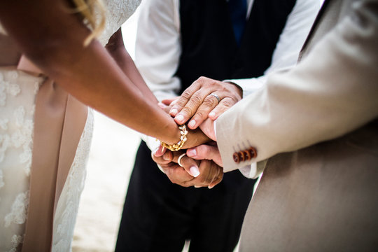 Close up of a husband and wife joining hands during the ceremony at a beach.,Koh Samui