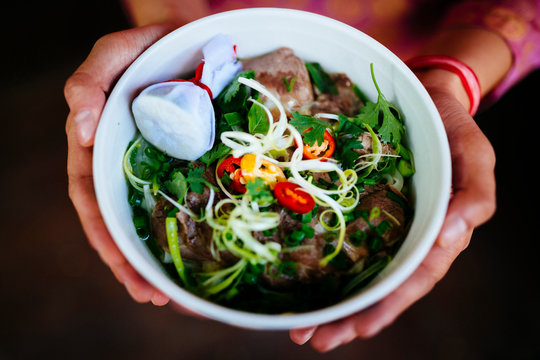High angle close up of person holding bowl of beef pho.,Hanoi