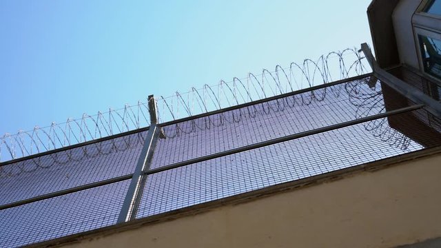 high prison wall with barbed wire, bottom view. watchtower
