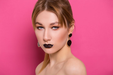 A beautiful young girl of European appearance with beautiful make-up on a pink background. Beauty Shooting