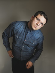 Relaxed millenial wearing blue denim shirt looking at camera. Hipster wearing jeans making funny face. millennial young man posing in the studio. Blue Filter - Portrait of an attractive cheerful man!