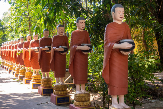 Row of Buddhist monk statues with red robes and alms bowls in the gardens of the Buddhist Temple at Siem Reap,Siem Reap
