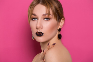 A beautiful young girl of European appearance with beautiful make-up on a pink background. Beauty Shooting