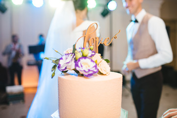 Happy bride and groom cut the wedding cake on wedding banquet. Elegant wedding cake with flowers...