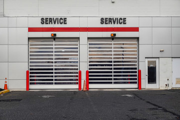 Closeup view of two overhead garage doors with the word service over each on the side of a white building
