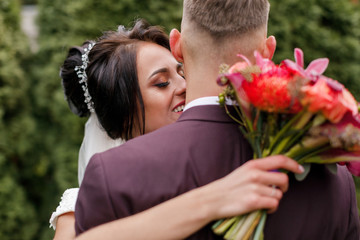 Beautiful bride and groom embracing and kissing on their wedding day. Happy romantic young couple celebrating their marriage