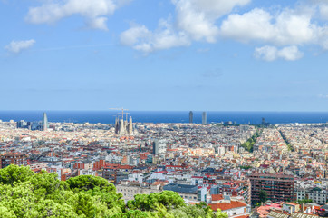 Fototapeta premium View of Spain's Barcelona from the Hill of Three Crosses in Güell Park over the Mediterranean Sea and the Eixample or New Town. In the center - Sagrada Familia