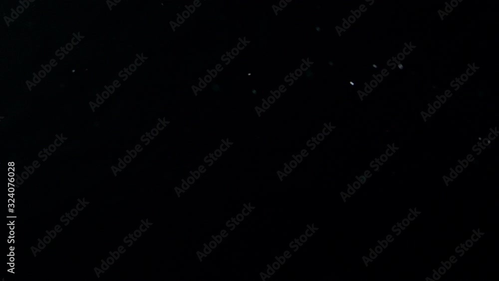 Poster real dust particles floating in front of a black background.