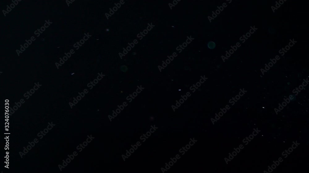 Poster real dust particles floating in front of a black background.