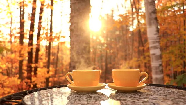 Two cups of coffee on a table with a beautiful sunset. Filmed in Canada during the autumn.