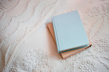 Two Plain Hardcover Books Stacked on a Bed