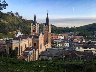 Fototapeta na wymiar Typical Antioquia Village with Big Catedral Surrounded of Green Hills of Pastures and Mountains Aerial View in Belmira, Antioquia / Colombia