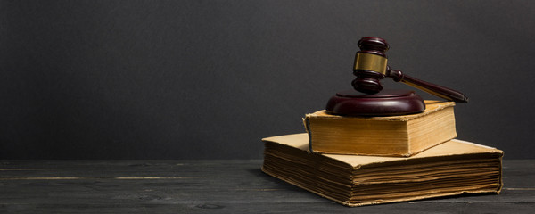 Law concept - Open law book with a wooden judges gavel on table in a courtroom or law enforcement office isolated on white background. Copy space for text.