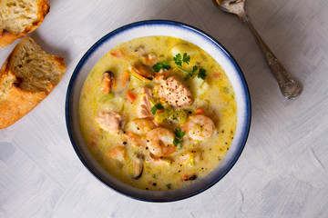 Bowl of seafood chowder with salmon on white background. Flat lay image. Copy space, room for text