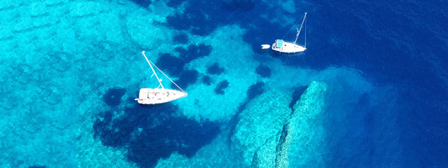 Fototapeta premium Aerial drone ultra wide photo of breathtaking turquoise exotic bay of blue lagoon in island of Paxos visited by sail boats, Ionian, Greece