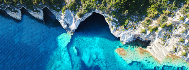 Aerial drone ultra wide photo of tropical white rocky bay of blue lagoon with turquoise clear waters, white volcanic caves and sail boats docked, island of Paxos, Ionian, Greece - obrazy, fototapety, plakaty