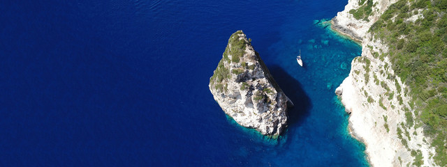 Aerial drone ultra wide photo of tropical rocky bay of Ortholithos with famous cave of Papanikolis...