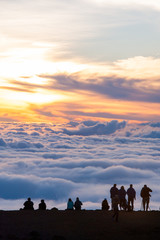 people watching sunset beyond sea of clouds
