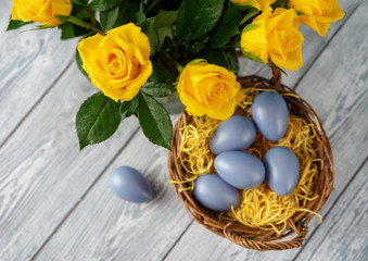 Easter eggs in basket and yellow roses seeing from above
