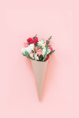 Roses bouquet in cone on pink background, flat lay, top view.