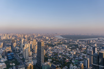 Fototapeta na wymiar Aerial view of skyline and cityscape of Bangkok, urban buildings along Chao Phraya river, with background of twilight sky before sunset with air pollution of pm 2.5 dust, from Mahanakorn Building.