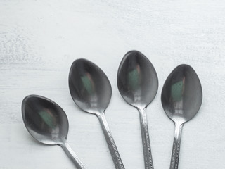 Four Spoons on a Rustic Board Painted with White Background